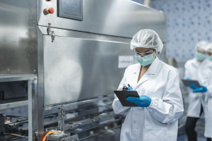 ouvrière dans une usine agroalimentaire, avec blouse et charlotte - norme iso 45001